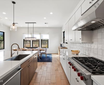 Contemporary kitchen and dining space with quartz countertops, statement lighting, and an open layout. Perfect for everyday living and entertaining in this Scottsdale luxury home.