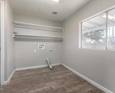 Convenient laundry area with built-in shelves and easy-care flooring, offering extra storage and everyday efficiency in this updated Phoenix home for sale.
