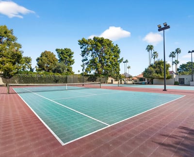 Community tennis courts surrounded by mature trees, offering a convenient recreational feature close to home.