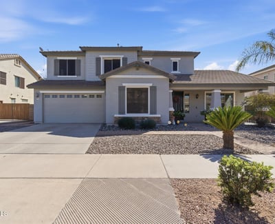 Attractive exterior of this Queen Creek property featuring a covered entry, desert landscaping, and attached garage in the popular Cortina community.