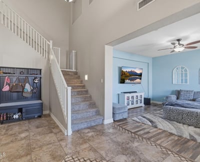 Welcoming entry foyer with soaring ceilings, tile flooring, and staircase leading to the loft and upper living areas of this spacious Queen Creek home.