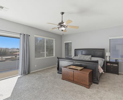 Beautiful primary bedroom with sliding glass doors leading to a private balcony, allowing fresh air and scenic neighborhood views.