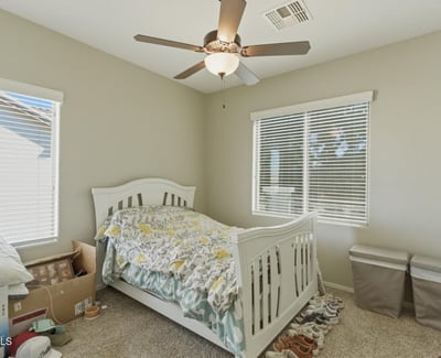 Comfortable secondary bedroom with plush carpet, ceiling fan, and large windows that bring in natural light, creating a welcoming space for guests or family.