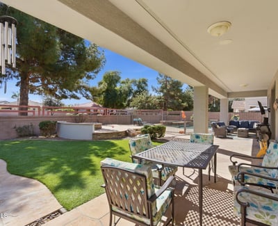 Shaded patio overlooking the landscaped yard and pool area, providing a comfortable outdoor living space for dining or relaxing.