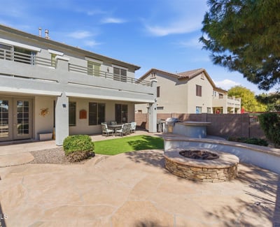 Backyard entertaining area featuring a built-in fire pit, spacious patio, and landscaped yard with pool views perfect for gatherings.