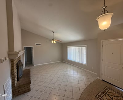 Interior perspective showing the open living space flowing toward the front entry. Neutral paint and tile flooring enhance the clean and inviting feel of this Glendale home.
