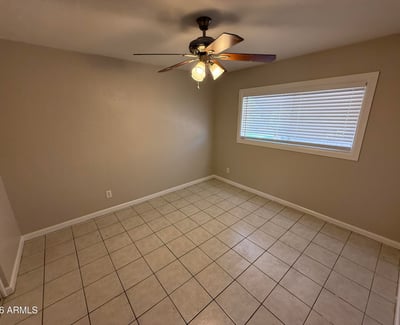 Bedroom with tile floors, ceiling fan, and soft neutral tones creating a relaxing environment. The space offers flexibility for a variety of bedroom or workspace uses.