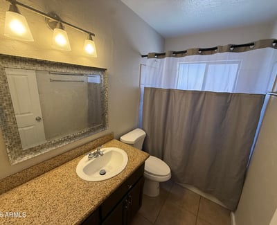Secondary bathroom featuring granite vanity counter, modern lighting, and full shower area. Functional layout provides convenience for guests and everyday living.