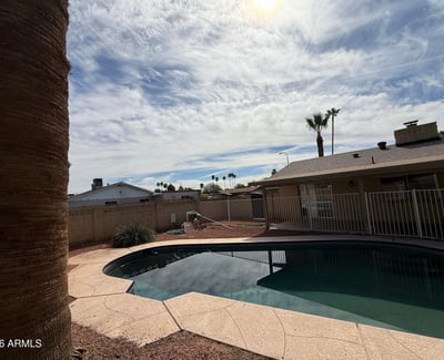 Inviting Pebble Tec pool surrounded by desert landscaping and privacy fencing. The outdoor space creates a refreshing retreat perfect for enjoying Glendale s warm weather.