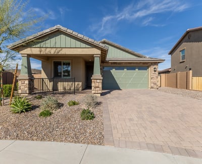Stunning Peoria home exterior with paver driveway, stone detailing, and desert landscaping. Offers low-maintenance living and strong curb appeal.