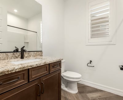 Guest bathroom featuring granite counters, wood cabinetry, and modern fixtures, blending style and everyday functionality.