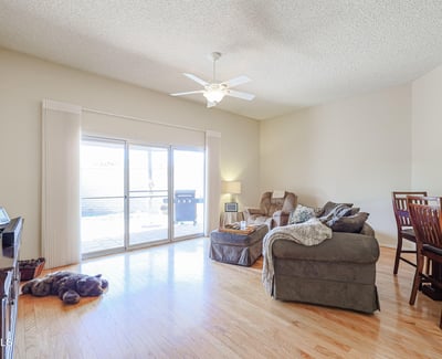 Open-concept living area with hardwood floors, ceiling fan, and large sliding doors leading to the backyard patio for indoor-outdoor living.