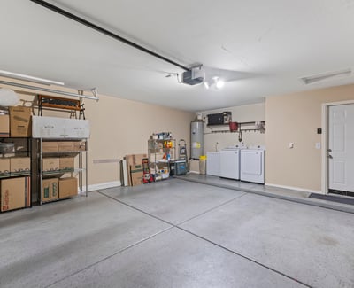 Spacious garage with shelving, laundry setup, and room for storage and vehicles, offering convenience and organization.