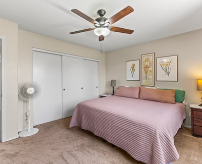 Comfortable primary bedroom with ceiling fan, plush carpet, and neutral finishes. A relaxing space designed for everyday living.