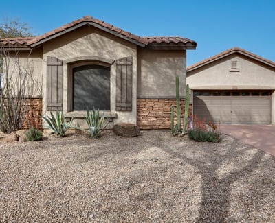 Attractive Phoenix home with desert landscaping, stucco exterior, and stone details, offering low-maintenance curb appeal and a welcoming entrance.