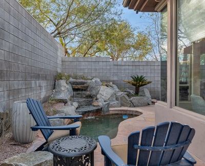 Serene backyard featuring a cascading water feature, patio seating, and low-maintenance landscaping in this Phoenix home.