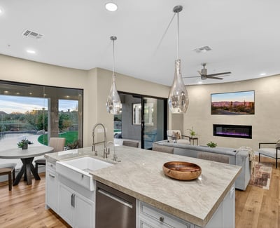 Spacious kitchen island with farmhouse sink and pendant lighting, overlooking the Scottsdale backyard with pool and lush landscaping.