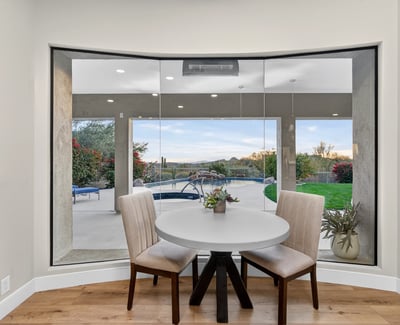 Bright dining nook with large windows framing views of the pool and patio, bringing natural light and Scottsdale outdoor beauty indoors.