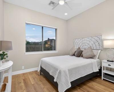 Bright Scottsdale bedroom with large window, wood flooring, and neutral finishes, offering a welcoming and versatile guest space.