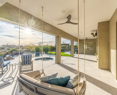 Scottsdale covered patio featuring modern hanging seating, ceiling fans, and open views to the pool and backyard.