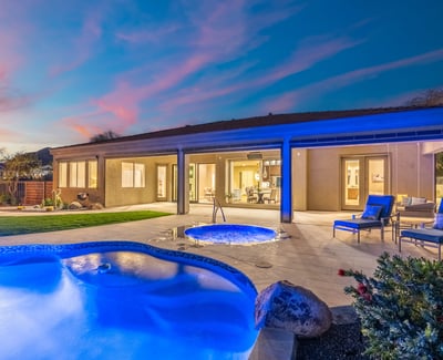 Scottsdale backyard featuring glowing spa, poolside seating, and covered patio, ideal for evening relaxation and entertaining.