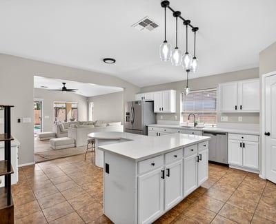 Spacious kitchen with large island, white cabinetry, and ample prep space. Open layout flows into living areas, making it ideal for gatherings in this Casa Grande property.