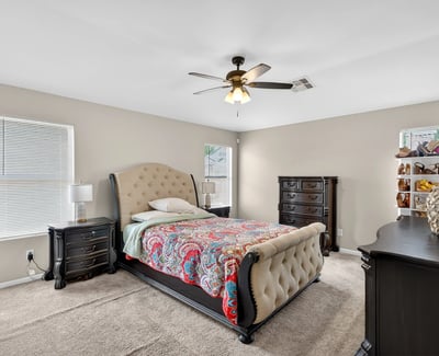 Generous primary bedroom with ceiling fan, soft carpet, and multiple windows. A relaxing retreat designed for comfort in this Casa Grande home.