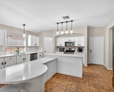 Bright open kitchen with large island, white cabinetry, and modern lighting. Perfect for entertaining and daily living in this Casa Grande home.