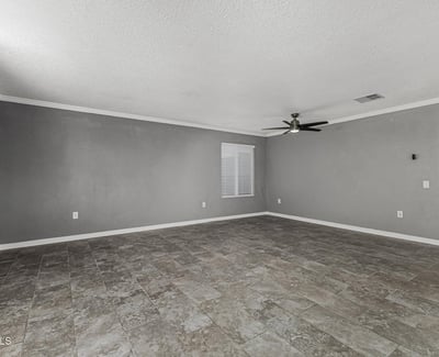 Spacious living area with modern flooring and ceiling fan. This Sun City home features an open floor plan perfect for relaxing or entertaining.
