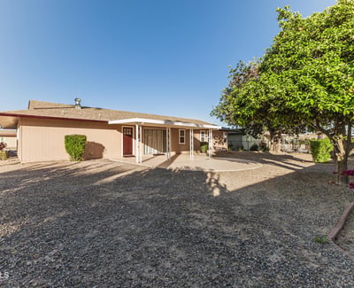 Expansive backyard with gravel landscaping and mature trees. This Sun City home provides a private outdoor retreat with minimal upkeep.
