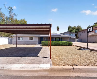 Well-maintained Phoenix property featuring a covered carport, paved parking, and desert landscaping perfect for low-maintenance multi-unit living.