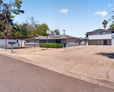 Wide-angle view showcasing the triplex layout, updated exterior, and spacious parking ideal for investors seeking Phoenix rental property.
