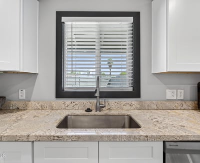 Window-lined sink area with granite counters and modern fixtures, creating a bright and functional kitchen workspace.