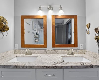 Stylish bathroom with dual sinks, granite counters, and updated lighting, designed for comfort and convenience.