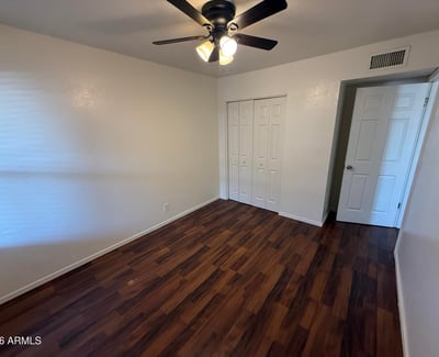 Comfortable bedroom featuring a ceiling fan, large closet, and attractive wood-look flooring. The spacious layout provides flexibility for bedroom furnishings while maintaining a bright and inviting atmosphere.