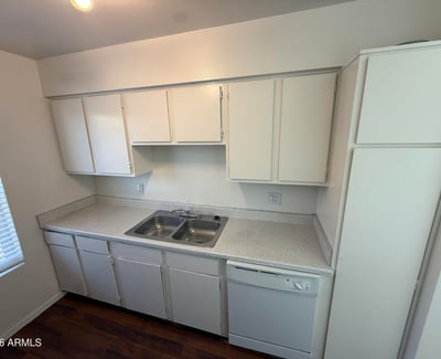Well-appointed kitchen with dual-basin sink, dishwasher, and ample cabinet storage. Large windows enhance the space with natural light while creating an inviting environment for meal preparation.