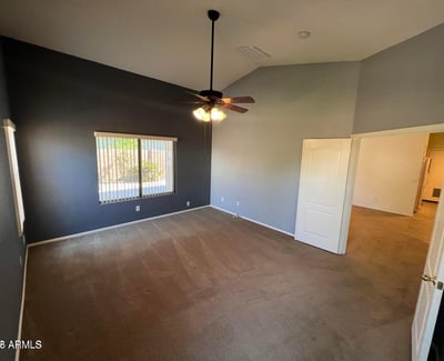 Large primary suite offering soaring ceilings, plush carpeting, and ample space for a full bedroom set. Multiple windows provide natural light and enhance the welcoming atmosphere.