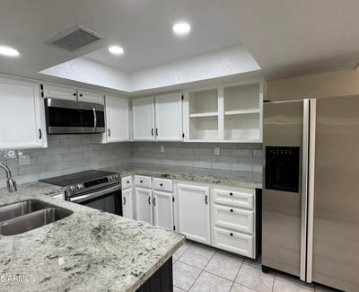 Updated kitchen featuring granite countertops, stainless steel appliances, refreshed cabinetry, and a modern tile backsplash. Designed to combine style, storage, and functionality.