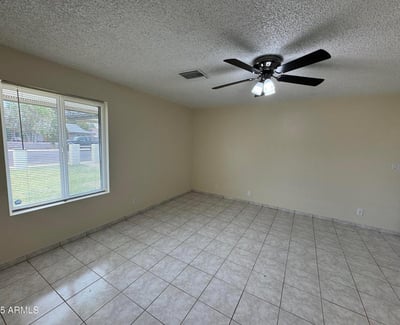 Expansive primary bedroom featuring tile flooring, a ceiling fan, and large windows that provide natural light throughout the day. This comfortable retreat