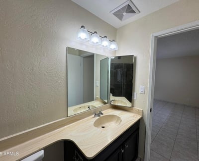 Well-designed primary bathroom featuring an oversized vanity, updated light fixtures, and abundant counter space. The functional layout provides comfort and convenience for daily routines.