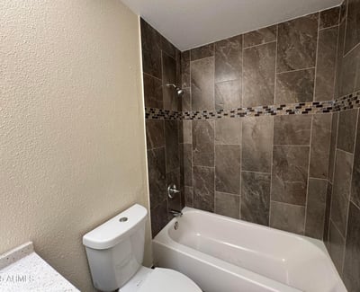 Attractive guest bathroom showcasing a stylish tile tub surround with decorative accent details and updated finishes. The refreshed design offers durability and timeless appeal.