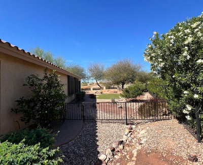 Beautiful side yard featuring flowering shrubs, decorative rock landscaping, gated access, and paver walkways that enhance both privacy and the home's low-maintenance outdoor design.
