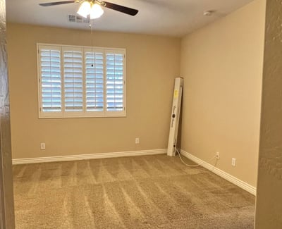Inviting secondary bedroom featuring soft carpeting, plantation shutters, ceiling fan, and abundant natural light. Ideal as a guest suite, hobby room, or private office space.
