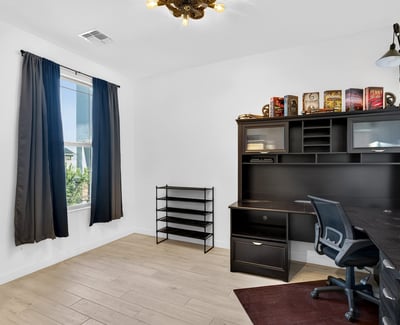 A spacious office with large windows, wood-look tile flooring, and ample room for desks or creative projects offers excellent flexibility for today's lifestyle in Surprise.