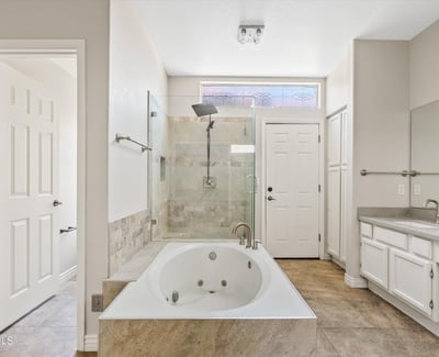 Relax in the spacious primary ensuite featuring a jetted soaking tub, oversized glass shower, updated fixtures, and abundant natural light. Thoughtfully designed for everyday comfort and luxury in Chandler.