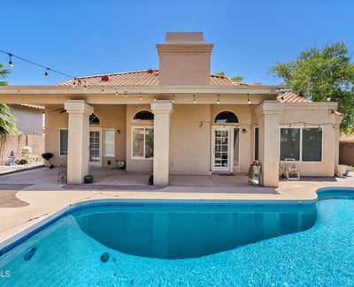 This covered patio overlooks the inviting swimming pool and landscaped backyard, offering comfortable outdoor living with plenty of space for entertaining and relaxing.