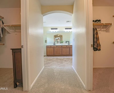 Convenient dressing area connecting dual walk-in closets with the spacious primary bathroom, providing exceptional organization and functionality for the owner's suite in this Waddell home.
