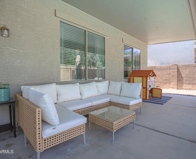 Relaxing covered patio featuring comfortable outdoor seating and views of the backyard entertaining space. A welcoming extension of the home's living area in this desirable Waddell property.