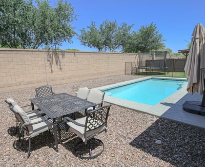 Outdoor dining space positioned beside the sparkling swimming pool, creating the perfect setting for entertaining and enjoying Arizona's outdoor lifestyle. A wonderful backyard feature in this Waddell home.