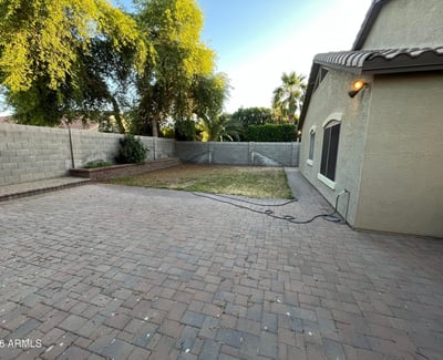 Generous backyard offers a spacious paver patio, grassy area, raised planter beds, and privacy walls, providing endless possibilities for entertaining or outdoor enjoyment.